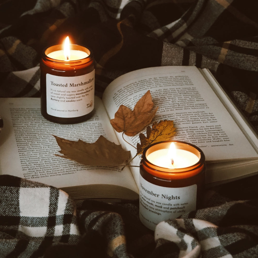 HEY CHALKY Duftkerze im Glas November Nights 155g - Moodbild mit zwei brennenden Kerzen, Buch und Decke